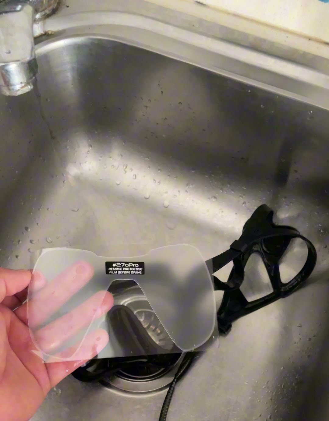 270Pro PURE anti-fog film, cut to shape, held beside a dive mask in a sink before application