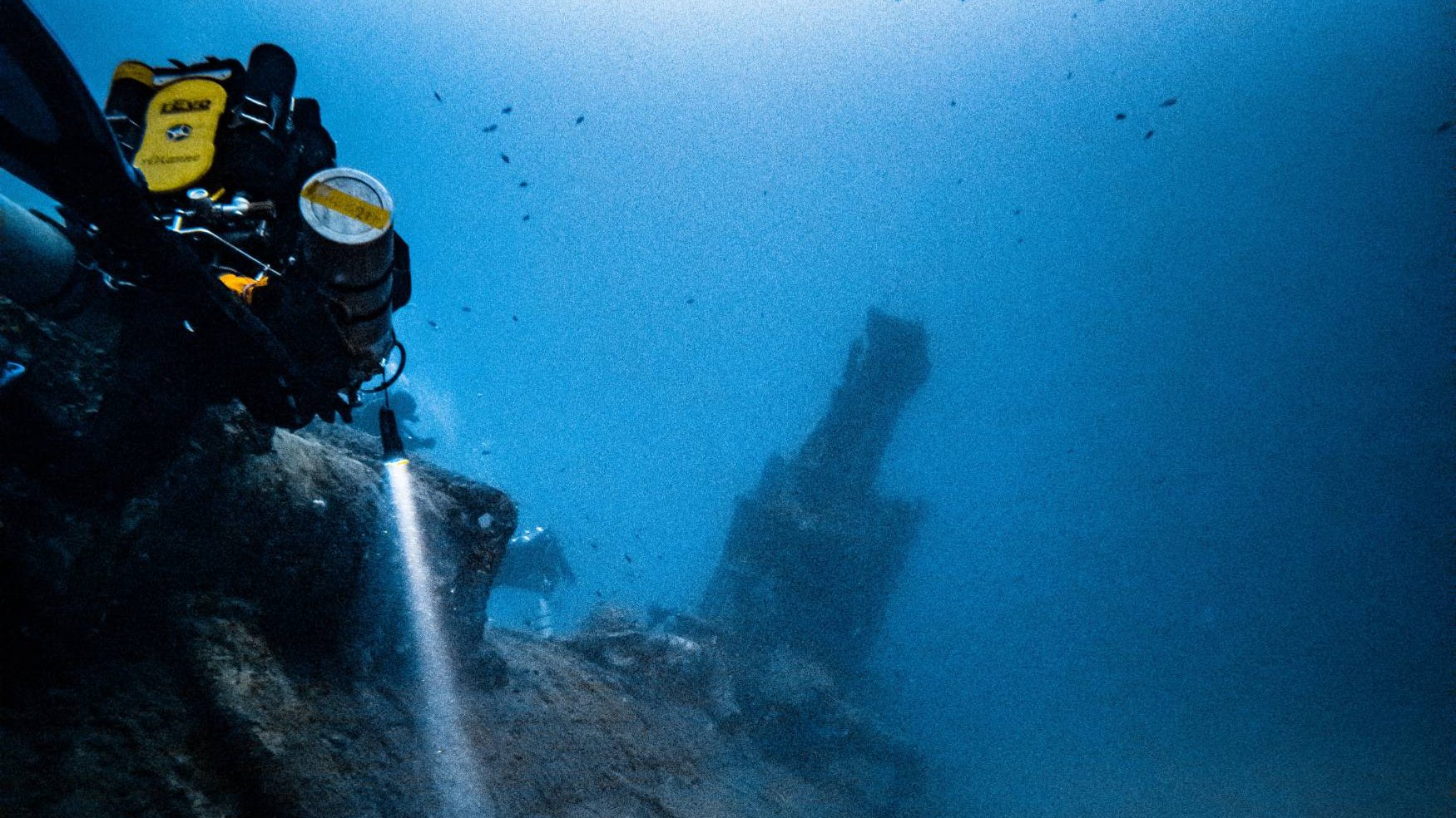 A rebreather diver lights the hull of a deep Malta wreck