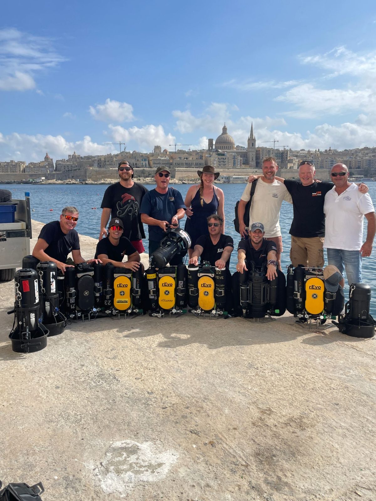 Team Barracuda and a row of rEvo rebreathers lined up on the quay with Valletta across the water behind them